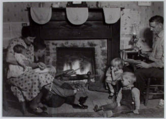 "Family group of Fletcher Carden, Route #1, Andersonville, Tennessee, a night-watchman at the bunkhouses at Norris Dam. His home is on the townsite of Norris and will be moved. Carden has 12 children. He is shown here repairing shoes at the fireside."