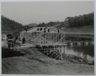 "Constructing the temporary warehouse near west end of the heavy duty bridge at the site of Norris Dam on the Clinch River. This will be used for a rigger shack later. The foundation cribs for the bridge can be seen in the river.", 11/01/1933