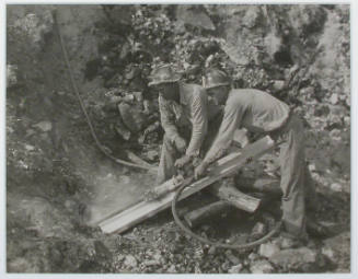 "Arthur Roberts and Sam Mynatt, drilling for a shot in boulder in roadway at Norris Dam.", 10/27/1933