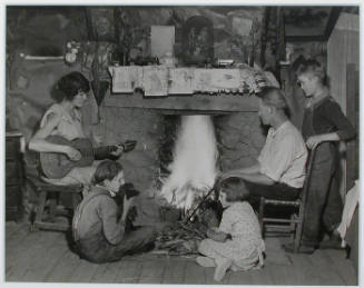 "The Glandon family around the fireplace in their home at Bridges Chapel near Loydston[sic], Tennessee. Glandon's wife plays both the guitar and the organ.", 10/31/1933