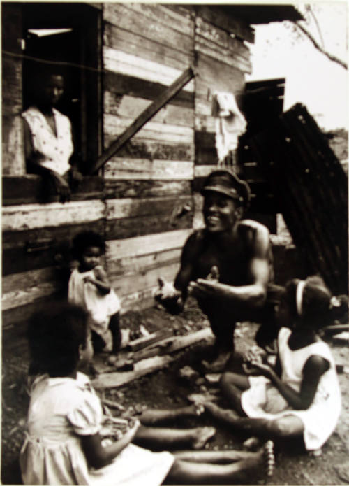 Man in hat playing with children on the ground, Panama